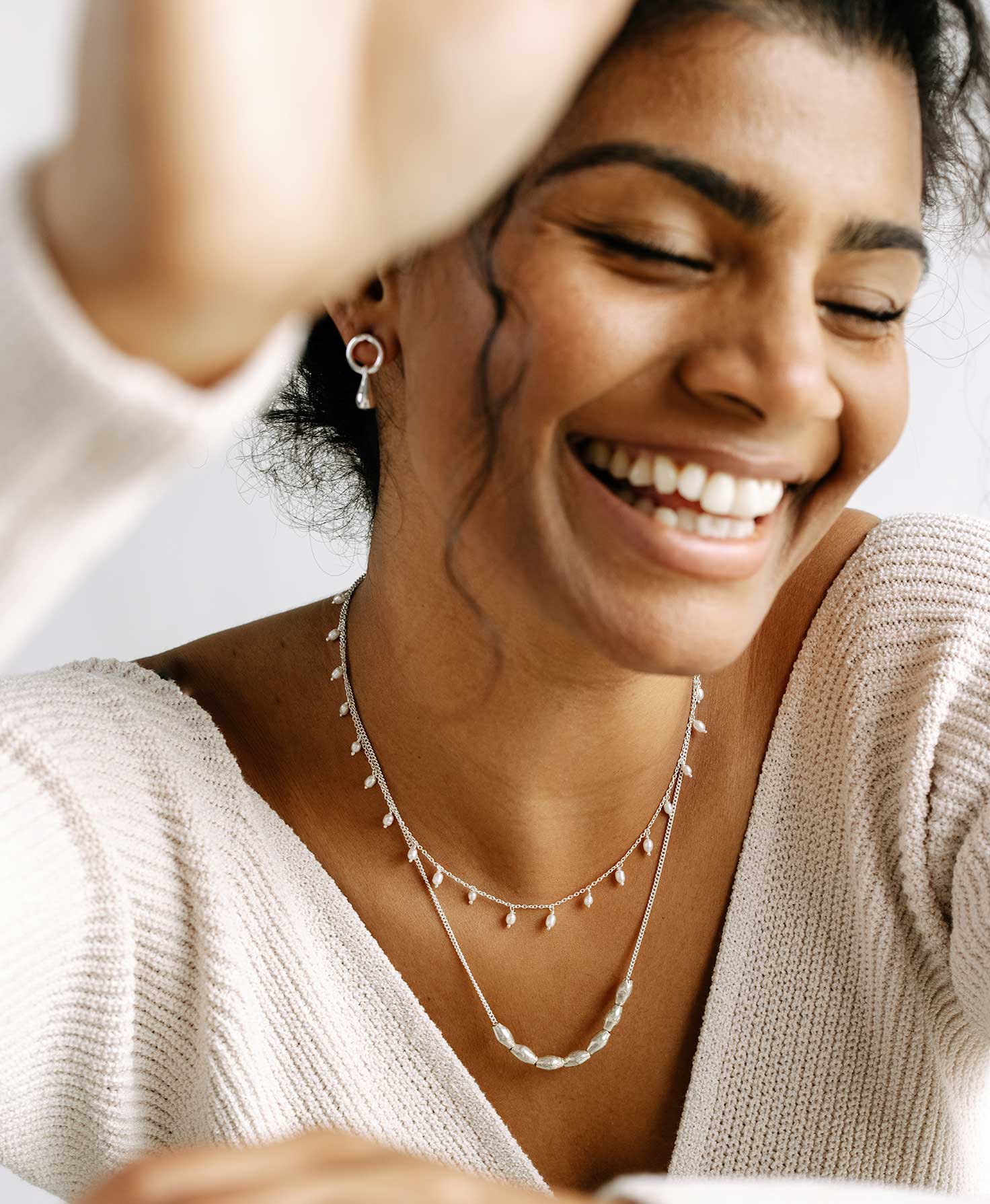 A model wears the Dew Drop Necklace layered with the Harmonize Necklace, another dainty silver necklace. To complete her sophisticated silver look, she wears a pair of earrings from the Silver Drop Earrings set.
